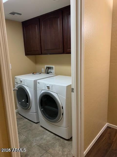 washroom featuring cabinet space, baseboards, visible vents, and washing machine and clothes dryer