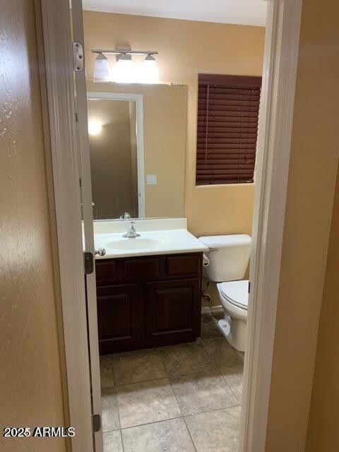 bathroom with toilet, tile patterned floors, and vanity