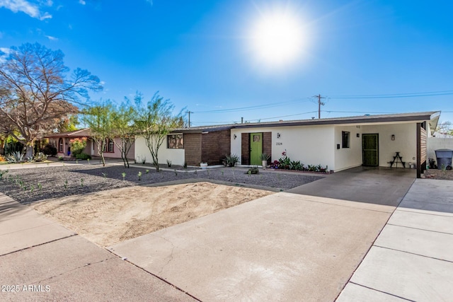 ranch-style house featuring an attached carport, concrete driveway, and stucco siding