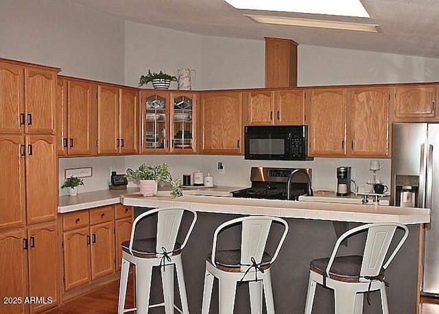 1181 S Cherokee Dr, Show Low, AZ 85901 - kitchen featuring stainless steel appliances, vaulted ceiling, light countertops, glass insert cabinets, and a breakfast bar