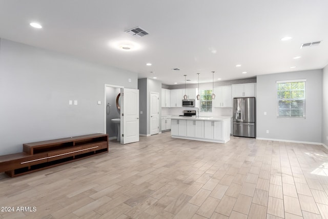 kitchen with light wood-type flooring, appliances with stainless steel finishes, a center island, and pendant lighting