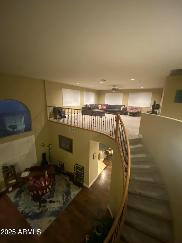 stairs with hardwood / wood-style floors and ceiling fan