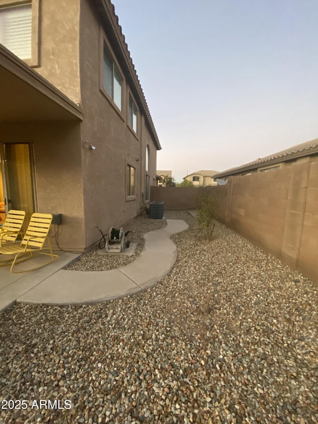 yard at dusk with central AC unit and a patio area