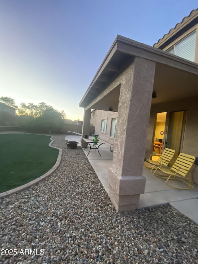 yard at dusk featuring a patio area