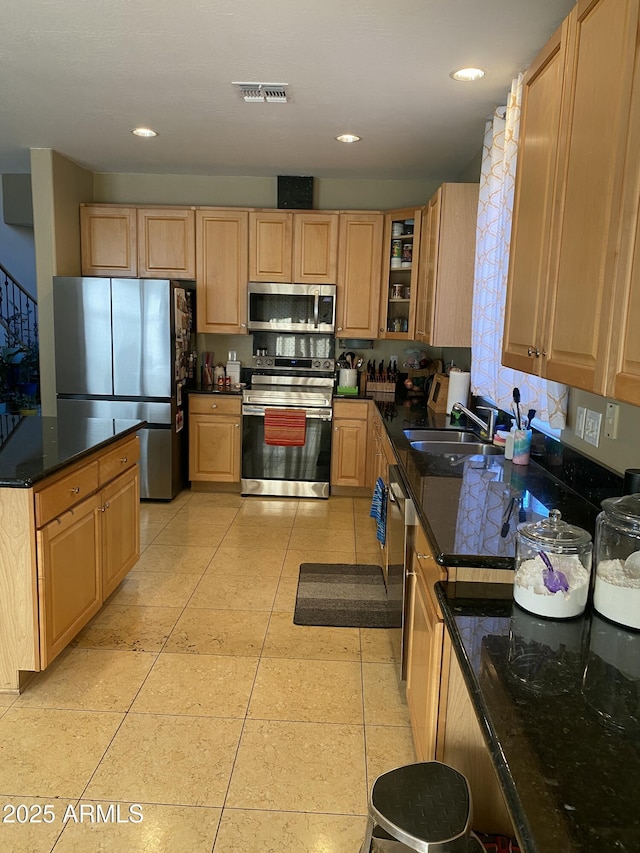 kitchen featuring sink, dark stone countertops, light tile patterned floors, stainless steel appliances, and light brown cabinets