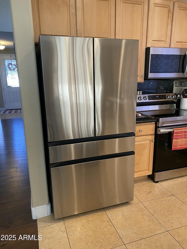 kitchen featuring stainless steel appliances, light tile patterned floors, light brown cabinetry, and decorative backsplash