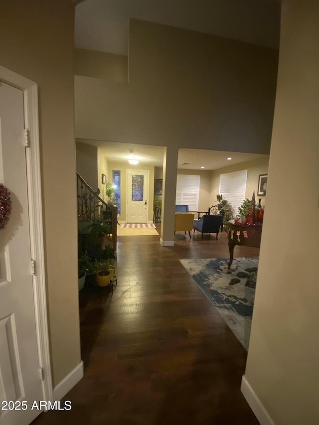 corridor with a towering ceiling and hardwood / wood-style floors