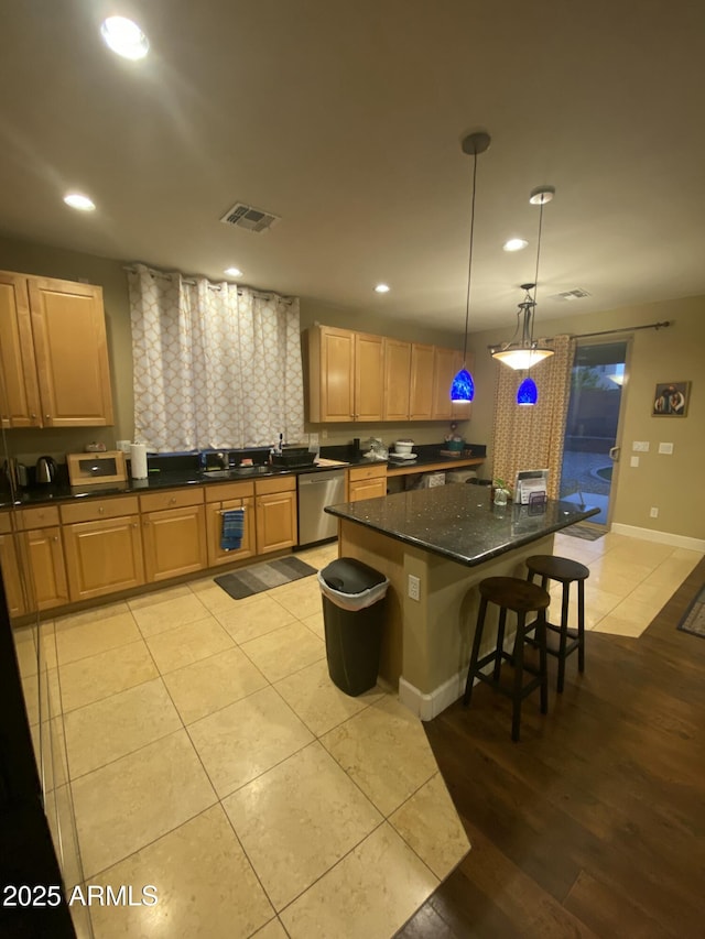 kitchen with light tile patterned flooring, decorative light fixtures, a center island, a kitchen breakfast bar, and dishwasher