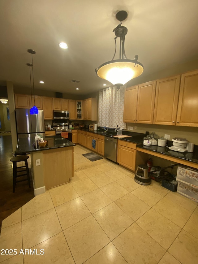 kitchen with pendant lighting, appliances with stainless steel finishes, a center island, and light tile patterned floors