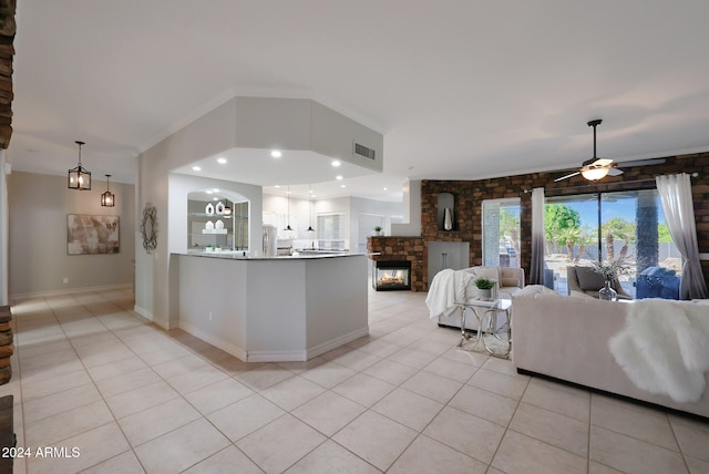 kitchen with a stone fireplace, stainless steel fridge, light tile patterned flooring, and ceiling fan