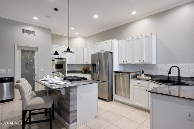 kitchen with white cabinets, dark stone counters, stainless steel appliances, sink, and decorative light fixtures