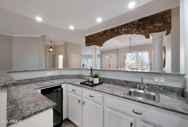 kitchen featuring hanging light fixtures, beverage cooler, and decorative columns