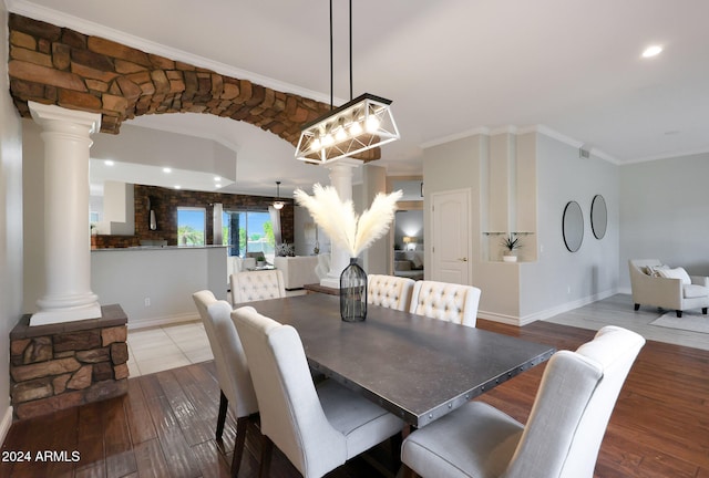 dining space with ornamental molding, ornate columns, and wood-type flooring