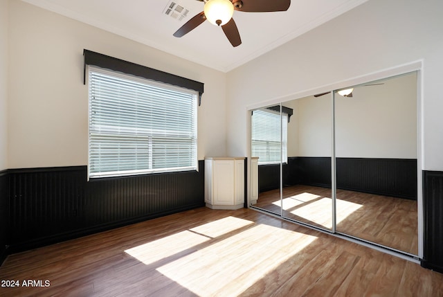 unfurnished bedroom featuring a closet, ornamental molding, wood-type flooring, and ceiling fan