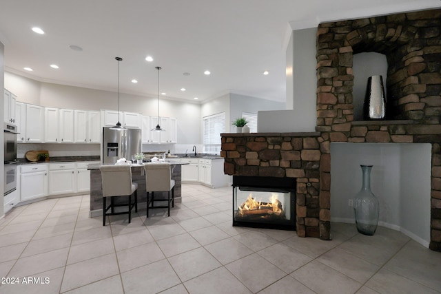 kitchen with hanging light fixtures, white cabinetry, stainless steel appliances, crown molding, and a breakfast bar area