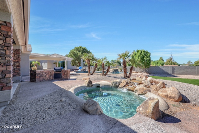 view of pool with a patio area, pool water feature, an outdoor kitchen, and a jacuzzi