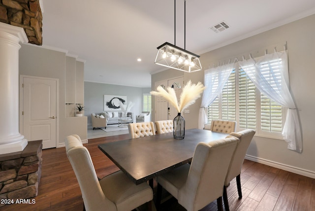 dining space featuring dark wood-type flooring, ornate columns, and crown molding