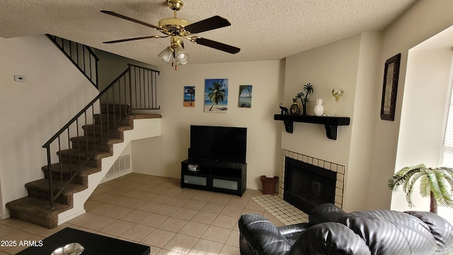 living room featuring light tile patterned flooring, ceiling fan, and a textured ceiling