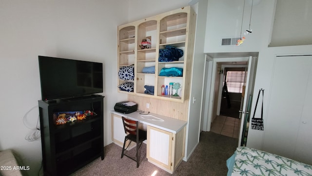 bedroom with built in desk and dark colored carpet