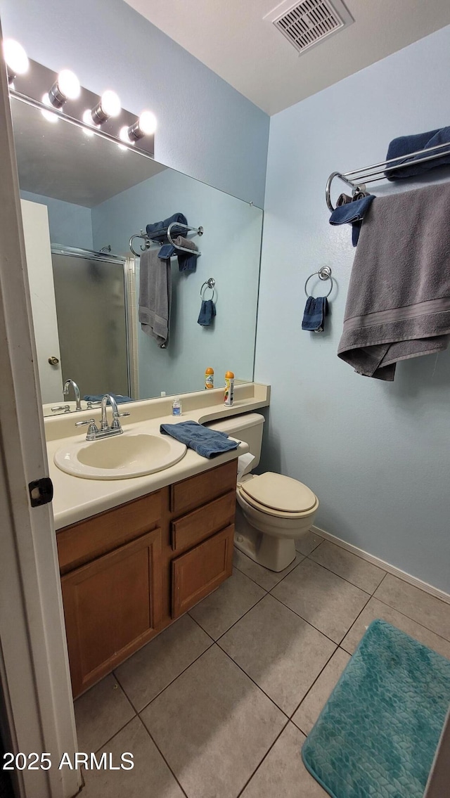 bathroom with tile patterned flooring, toilet, vanity, and a shower with shower door