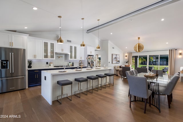 kitchen featuring pendant lighting, vaulted ceiling with beams, appliances with stainless steel finishes, white cabinetry, and a breakfast bar area