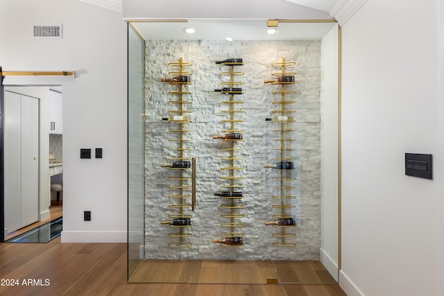 wine room with wood-type flooring and crown molding