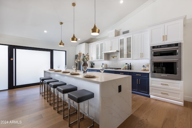 kitchen with lofted ceiling, white cabinetry, blue cabinetry, and a breakfast bar