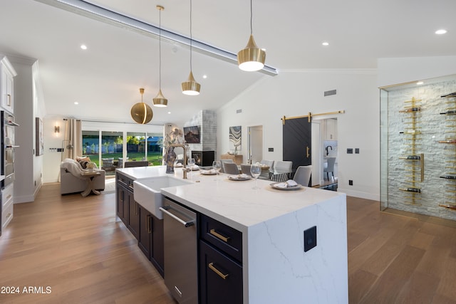 kitchen with hardwood / wood-style floors, a barn door, stainless steel dishwasher, and lofted ceiling