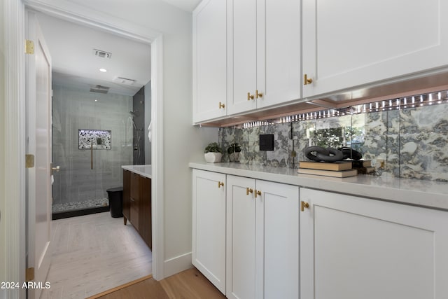 bar featuring white cabinets, light wood-type flooring, and tasteful backsplash