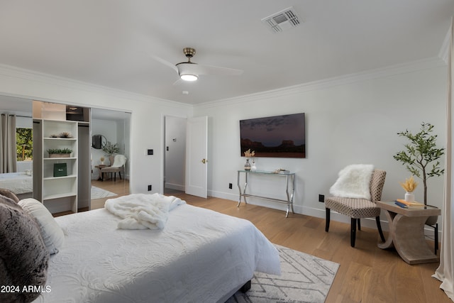 bedroom with ceiling fan, light wood-type flooring, crown molding, and a closet