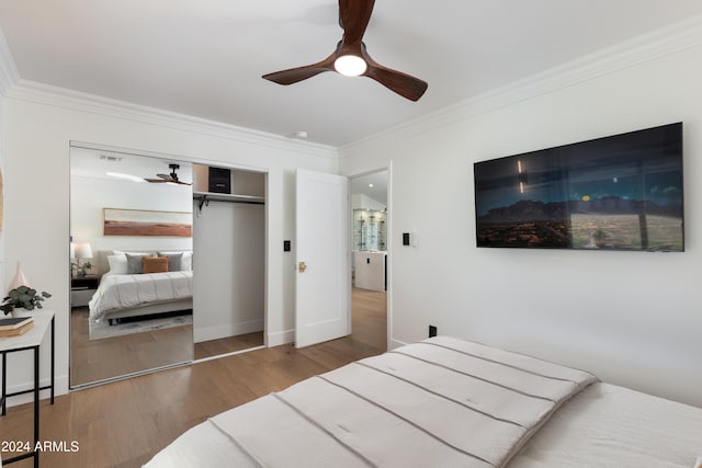 bedroom featuring hardwood / wood-style floors, a closet, ceiling fan, and ornamental molding