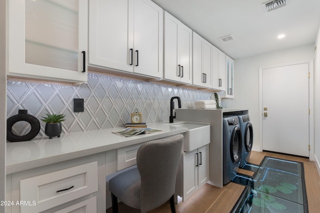 clothes washing area with washer and dryer, light hardwood / wood-style floors, and sink