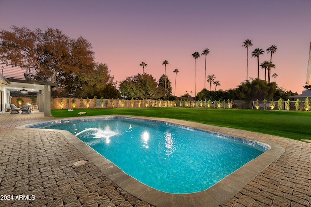 pool at dusk featuring a patio area and a yard