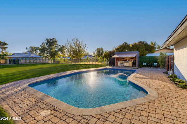 view of swimming pool featuring pool water feature, a yard, a patio, and an outdoor structure