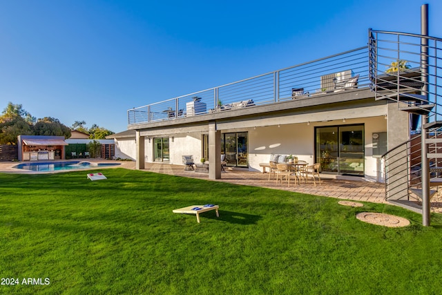 back of property featuring a balcony, a patio area, and a lawn