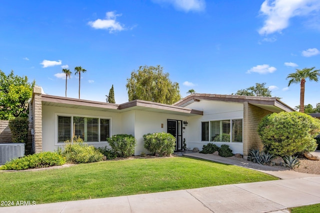 ranch-style house featuring stucco siding, cooling unit, and a front yard