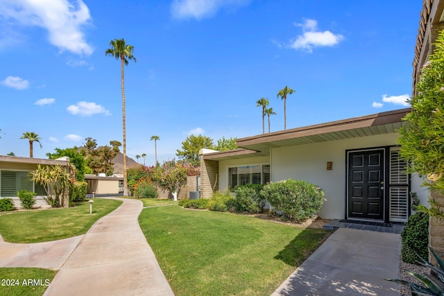 ranch-style house featuring a front lawn and stucco siding