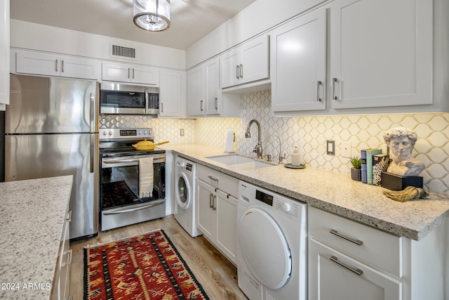 kitchen with light hardwood / wood-style flooring, stainless steel appliances, sink, and washer / dryer