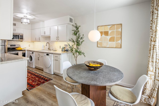 kitchen with washer / clothes dryer, a sink, appliances with stainless steel finishes, and light wood-style floors