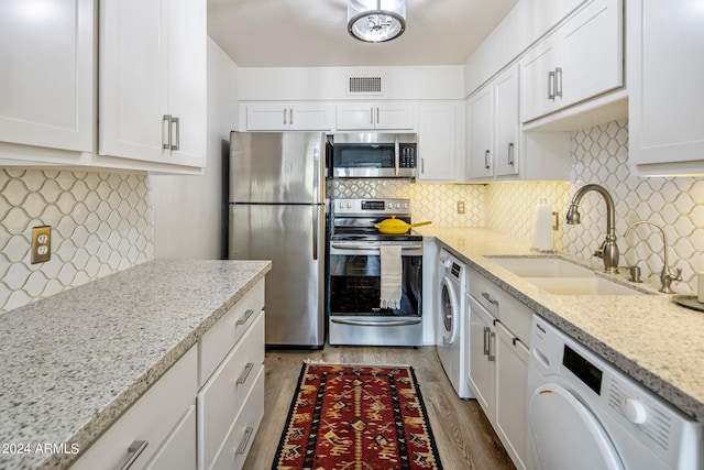 kitchen with stainless steel appliances, washer / clothes dryer, visible vents, and a sink