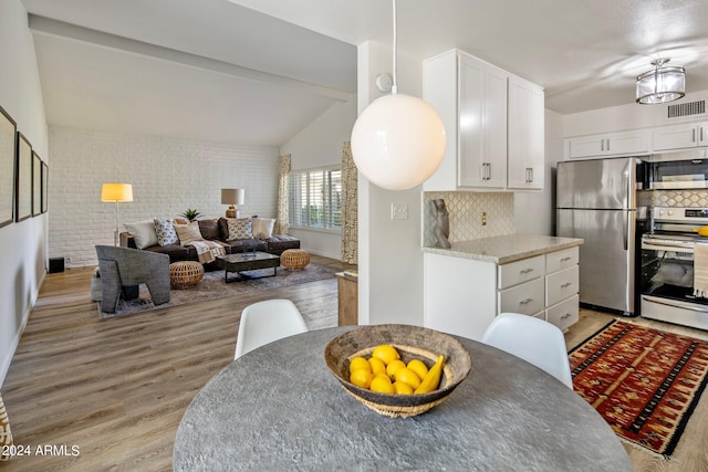 kitchen with visible vents, stainless steel appliances, light wood-type flooring, white cabinetry, and backsplash