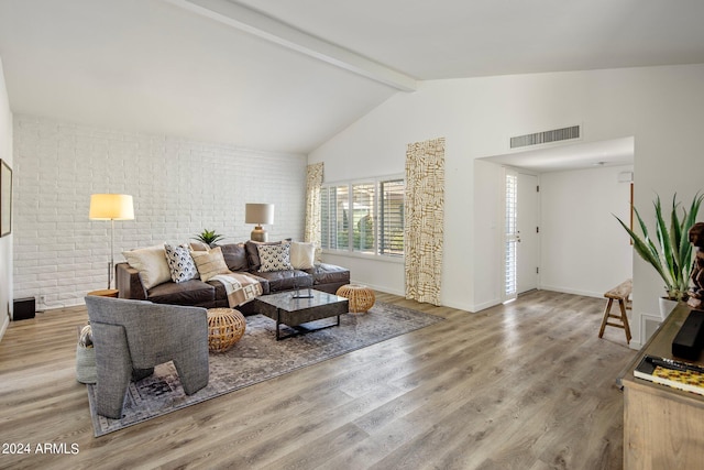 living area with visible vents, brick wall, wood finished floors, and beam ceiling