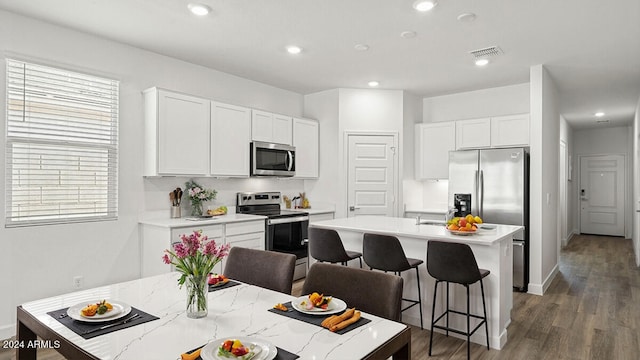 kitchen featuring white cabinetry, dark hardwood / wood-style flooring, an island with sink, and stainless steel appliances