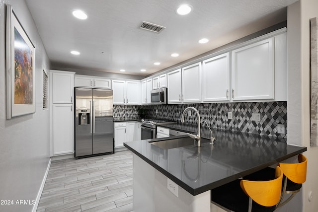 kitchen featuring white cabinetry, kitchen peninsula, a kitchen bar, and stainless steel appliances