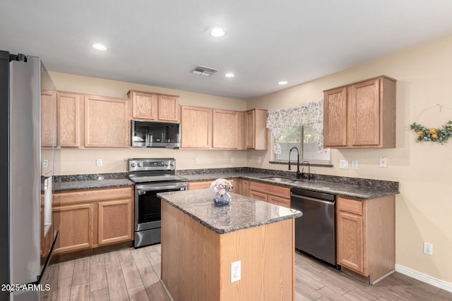 kitchen with a center island, sink, stainless steel appliances, and light brown cabinetry