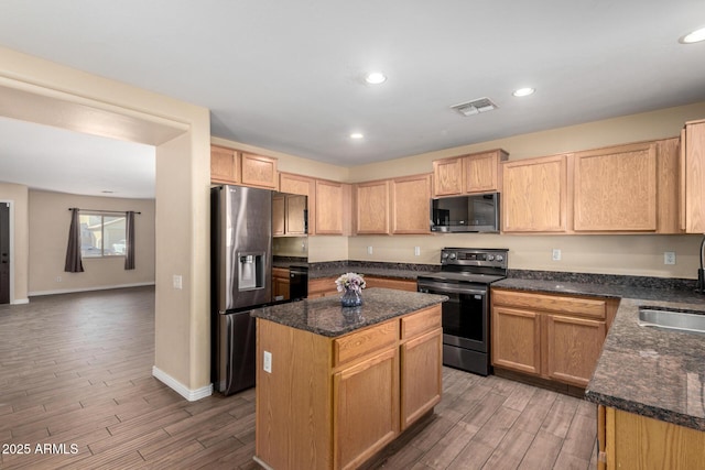 kitchen with a center island, dark stone countertops, sink, and appliances with stainless steel finishes