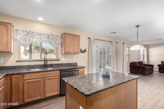 kitchen with sink, decorative light fixtures, dark stone countertops, dishwasher, and a center island