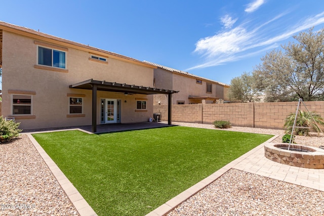 rear view of property with a lawn, a patio area, an outdoor fire pit, and french doors