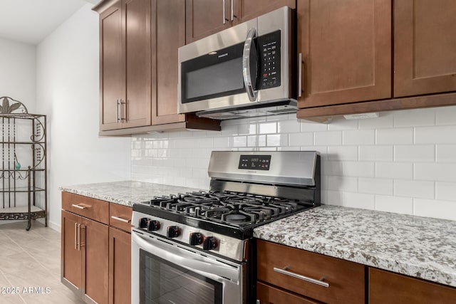 kitchen featuring light stone counters, appliances with stainless steel finishes, tasteful backsplash, and light tile patterned floors