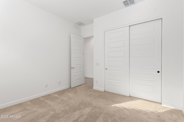 unfurnished bedroom featuring light carpet and a closet